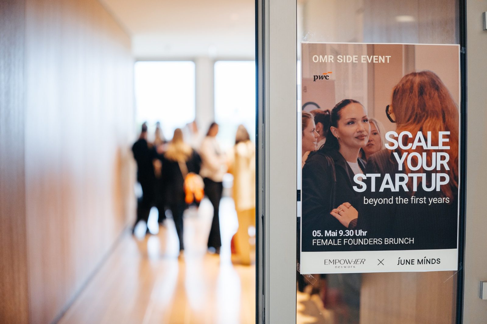 Plakat „Scale your Startup beyond the first years“ am Eingang des PwC-Office